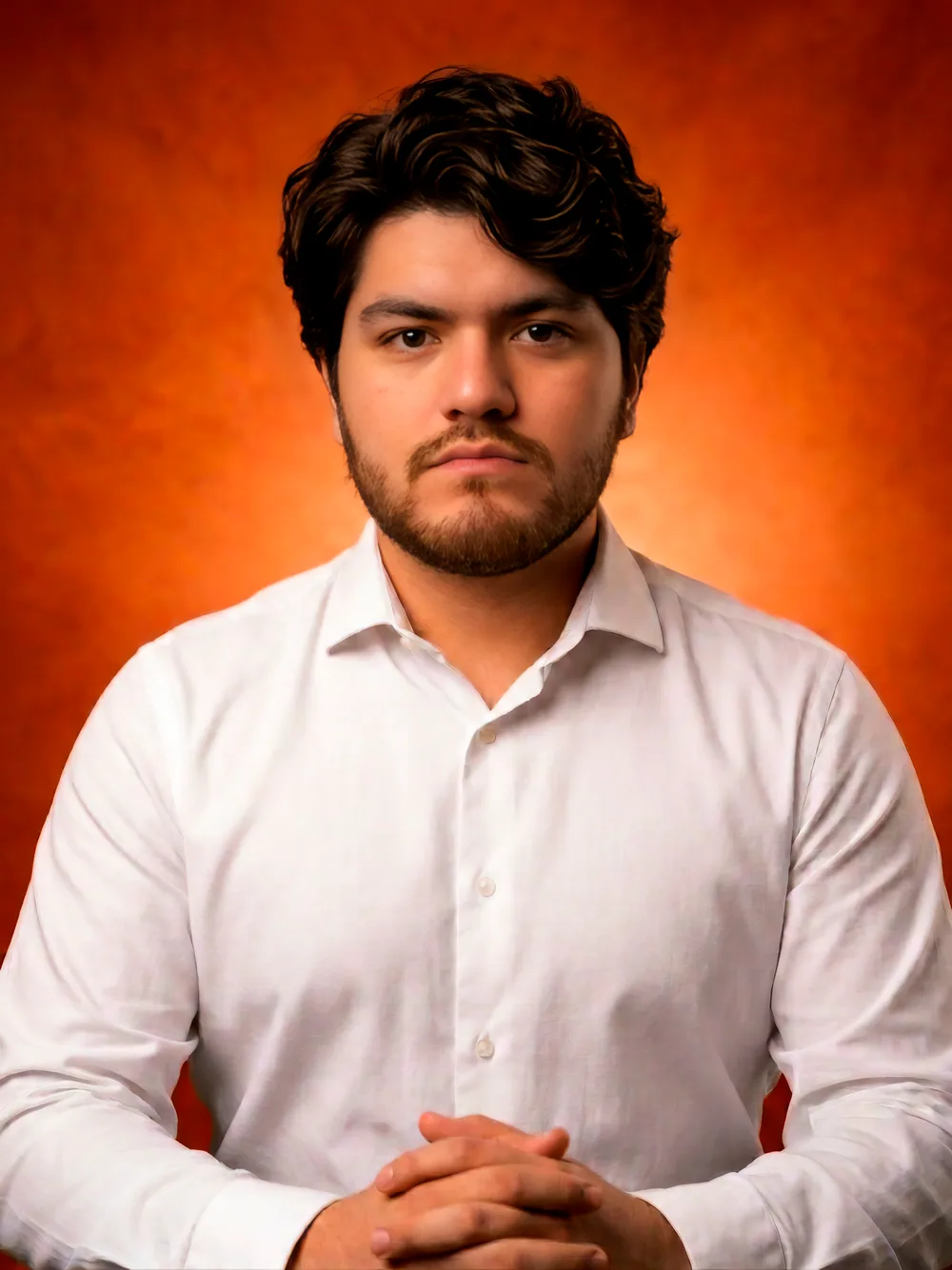 Retrato de Francisco Arca, camisa blanca sobre fondo naranja.